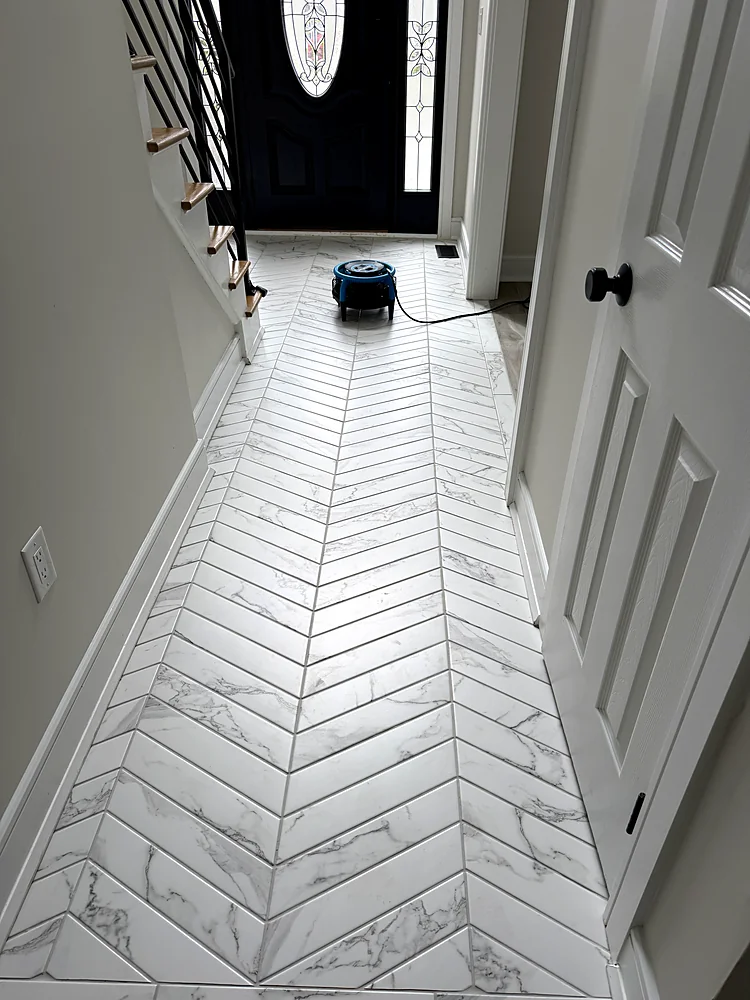 Marble-look chevron tile hallway drying with an air mover after cleaning